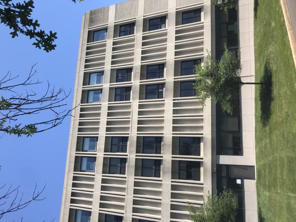 Multi-story concrete panel office building with window openings and landscaped lawn